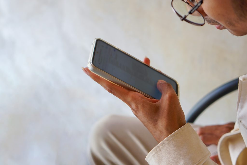 Person scrolling mobile phone and wearing glasses