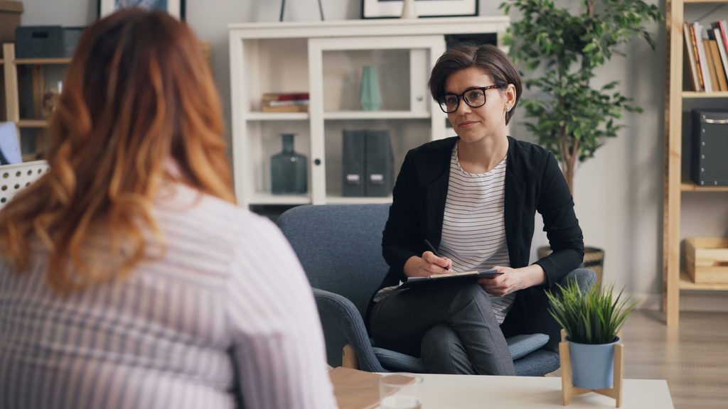 Therapist in session with a patient and writing in a notebook